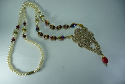 High angle view of necklace on leaf over white background