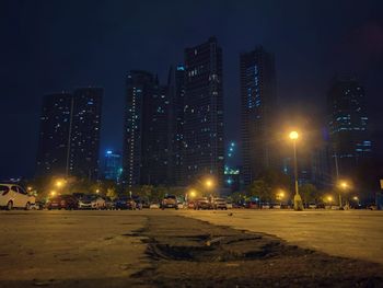 Cars on illuminated street with buildings in background in city at night