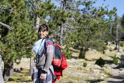 Woman standing by plants against trees