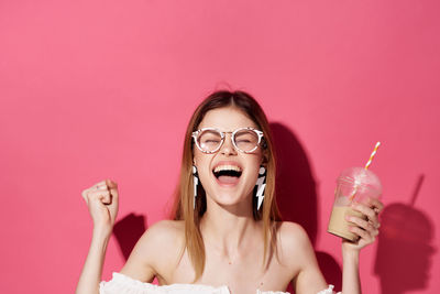 Cheerful young woman holding coffee against colored background