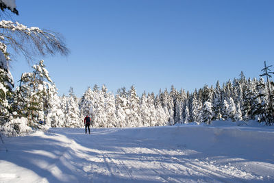 Man skiing on snow covered field against clear sky