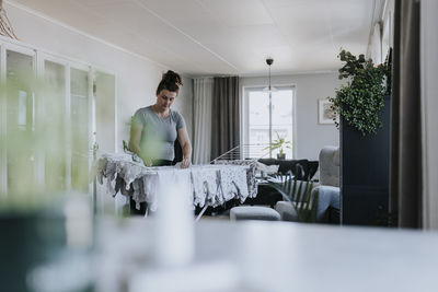 Pregnant woman doing housework and hanging baby clothes on drying rack