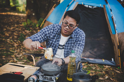 Man on camping holiday frying egg in pan