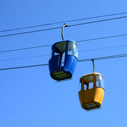 Low angle view of overhead cable car against blue sky