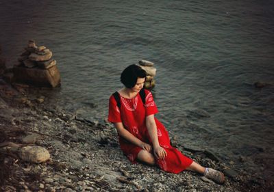 High angle view of girl sitting on rock at shore