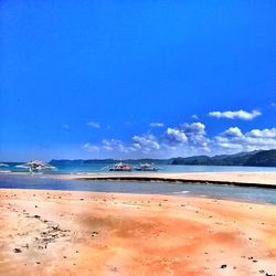 Scenic view of beach against blue sky