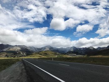 Scenic view of road by mountains against sky