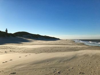 Scenic view of beach against clear blue sky