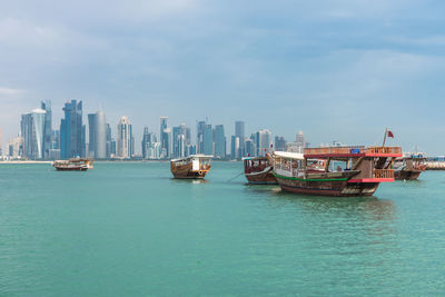 The skyline of doha, qatar with traditional dhows in the foreground.