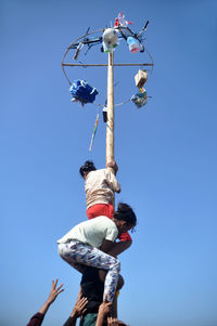 Low angle view of people against clear blue sky