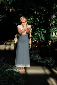 Portrait of a young woman standing against plants