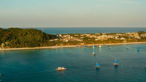 Aerial view of sailing yachts on the sandy beach of boracay island at sunset time. 