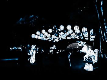 Low angle view of illuminated lighting equipment against black background