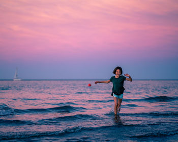 Full length of young woman standing on beach during sunset