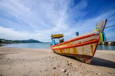 Fishing boat on beach against sky