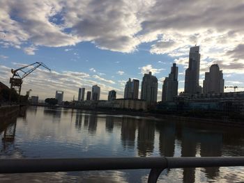 Scenic view of river by city buildings against sky