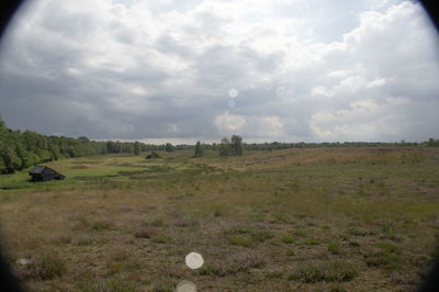 Scenic view of grassy field against cloudy sky