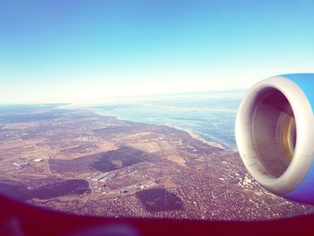 Close-up of airplane flying over sea against clear sky