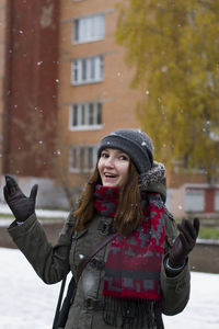 Portrait of woman playing with snow against building