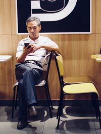Man using smart phone sitting on chair at cafe