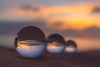 Close-up of crystal ball on beach against sky during sunset