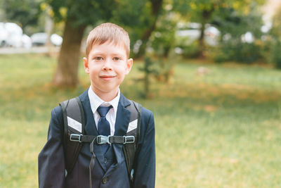 A schoolboy in a school uniform and a backpack stands on the street. boy in school uniform. 