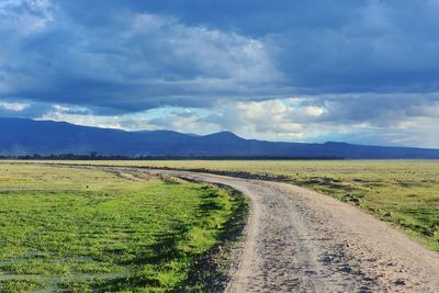 Road amidst field against sky