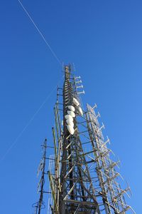 Low angle view of communications tower against clear blue sky