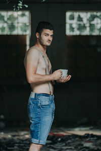 Portrait of young man holding camera while standing outdoors