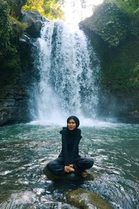 Female tourist playing in the waterfall