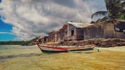 Boat moored on beach against sky