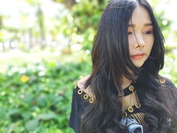 Young woman looking away against plants