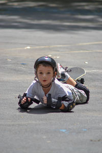 Full length portrait of boy lying down on road