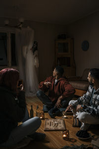 Terrified multiracial friends with ouija board looking at ghost in cabin