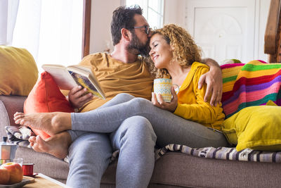 Cheerful mature couple embracing while sitting on sofa