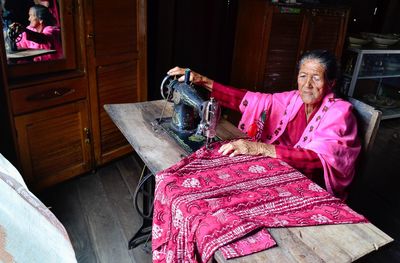 High angle view of woman stitching fabric in workshop