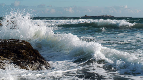 Waves splashing on sea against sky