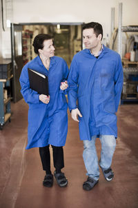 Male and female electricians discussing while walking in factory