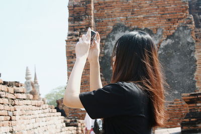 Rear view of woman standing against brick wall