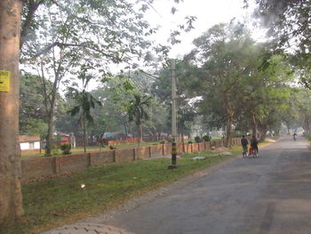 People walking on footpath by road against sky