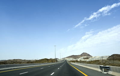 Road leading towards mountain against sky