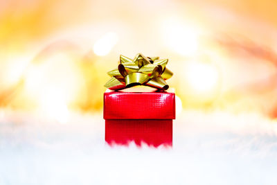 Close-up of red christmas present against illuminated string lights on rug