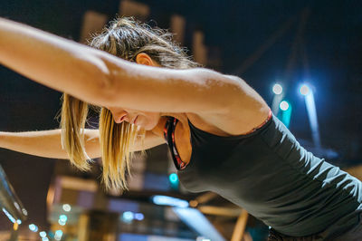 Unrecognizable exhausted young woman runner resting after training at night