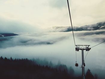 Overhead cable car against sky during foggy weather