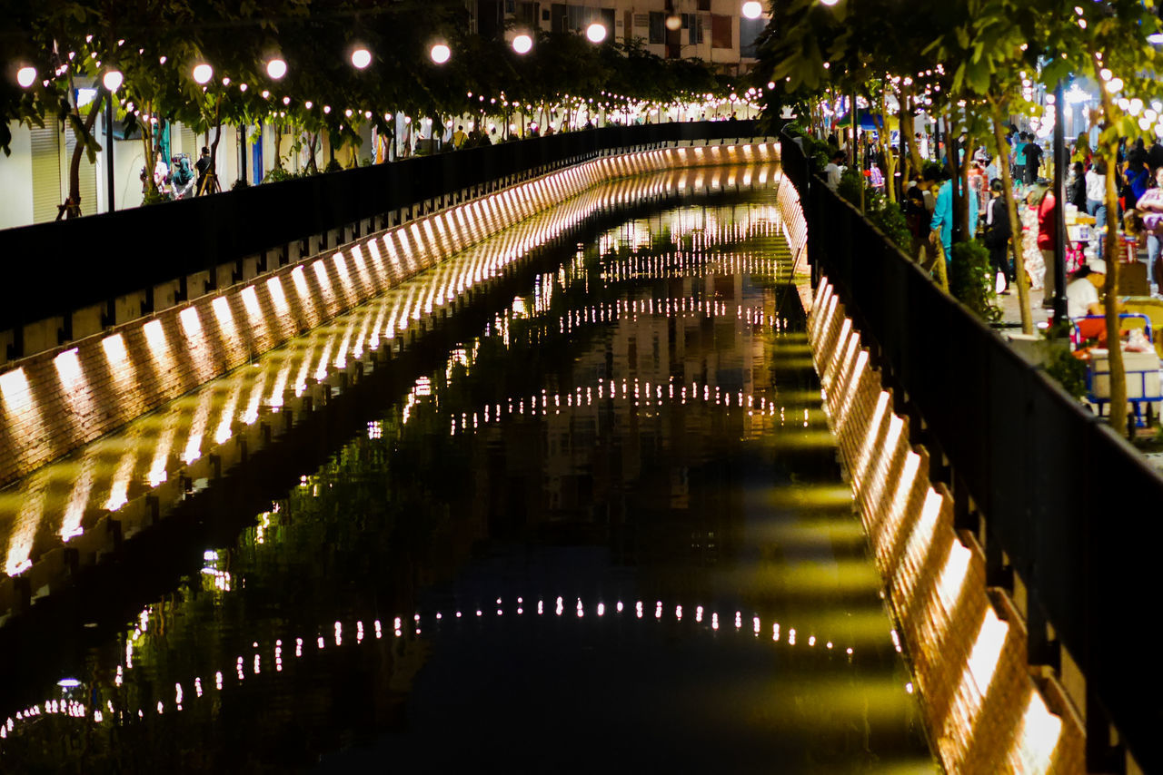 REFLECTION OF BRIDGE IN RIVER AT NIGHT