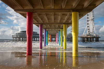 Underneath scheveningen pier at north sea beach with colorful poles