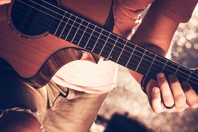 Midsection of man playing guitar