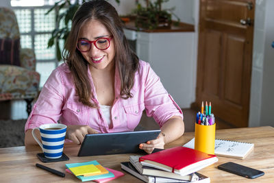 Young woman using mobile phone while sitting on table