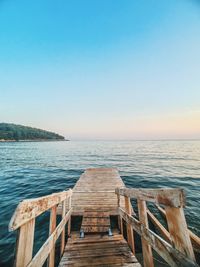 View of pier on calm blue sea against clear sky