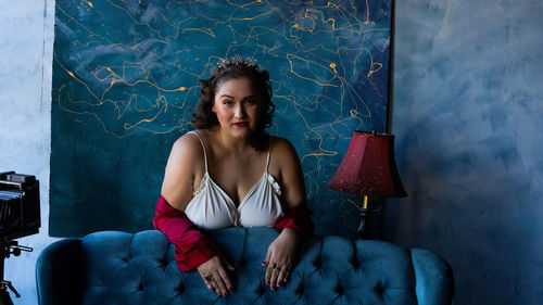 Portrait of young woman sitting against wall